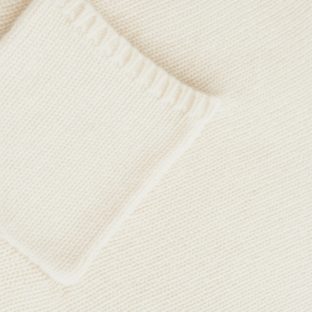 Close-up of a textured ecru white knitted fabric with pocket detail